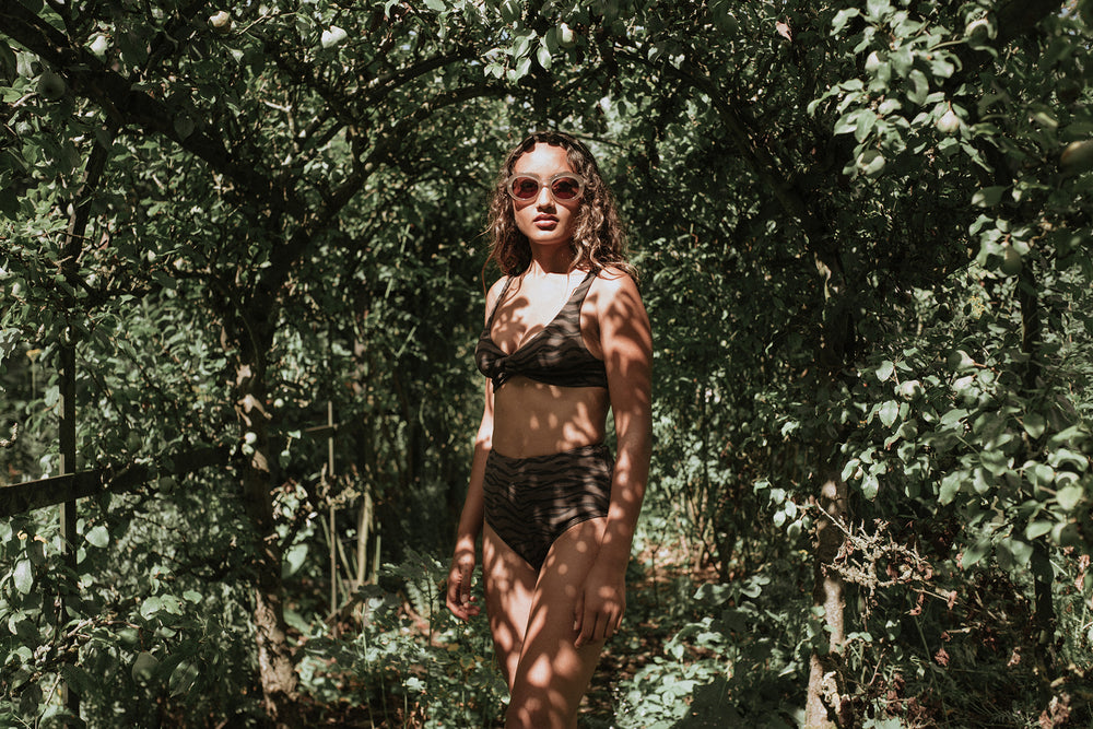 Woman standing in front of forest wearing PRISM bikini